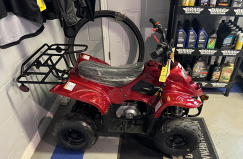 A Red Four-wheeler Atv Parked Neatly In A Spacious Garage