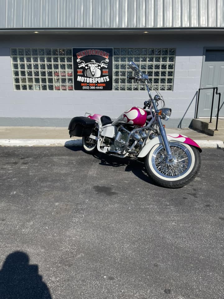 A Pink Motorcycle Is Parked In Front Of A Modern Building