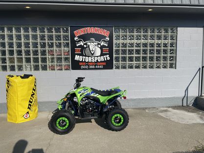 A Green And Black Atv Parked In Front Of A Building